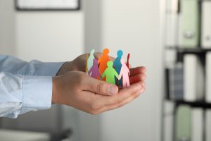 person holding a team of cutout people in their hands